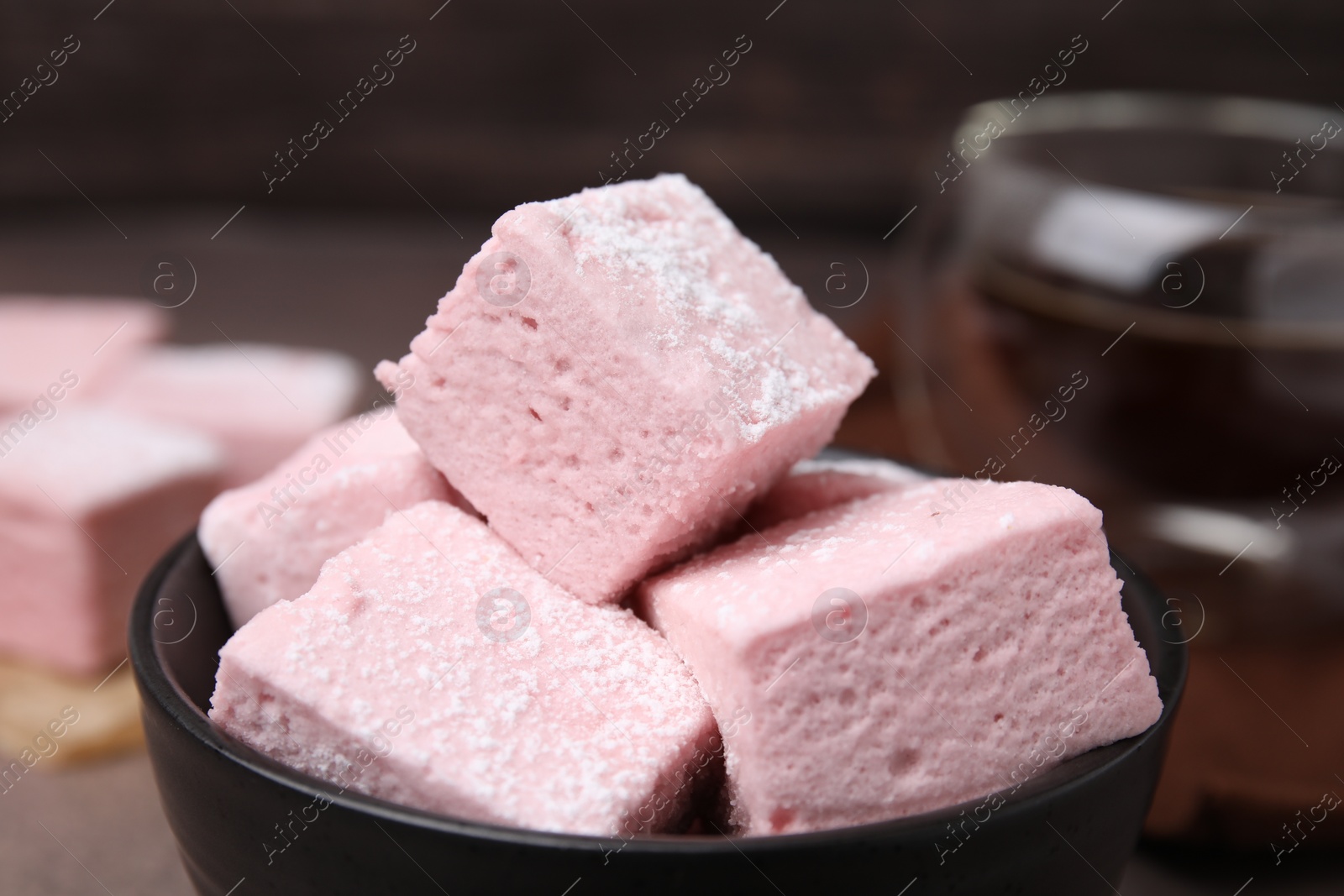 Photo of Bowl of delicious sweet marshmallows with powdered sugar, closeup