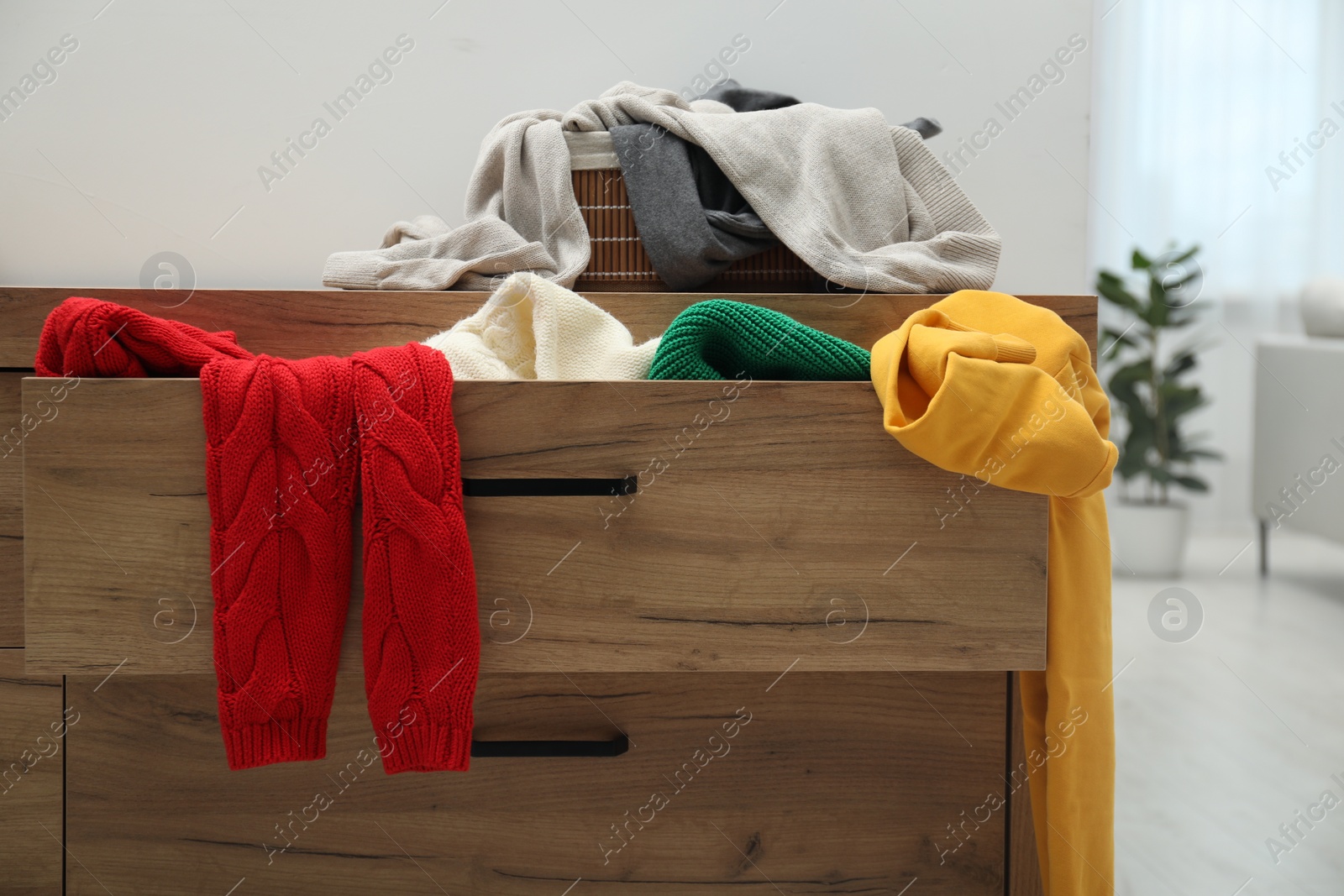 Photo of Cluttered chest of drawers indoors. Clothes in mess