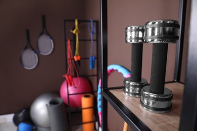 Photo of Metal dumbbells on shelf in room with other sports equipment, space for text