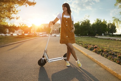 Photo of Young woman with kick scooter in sunny park