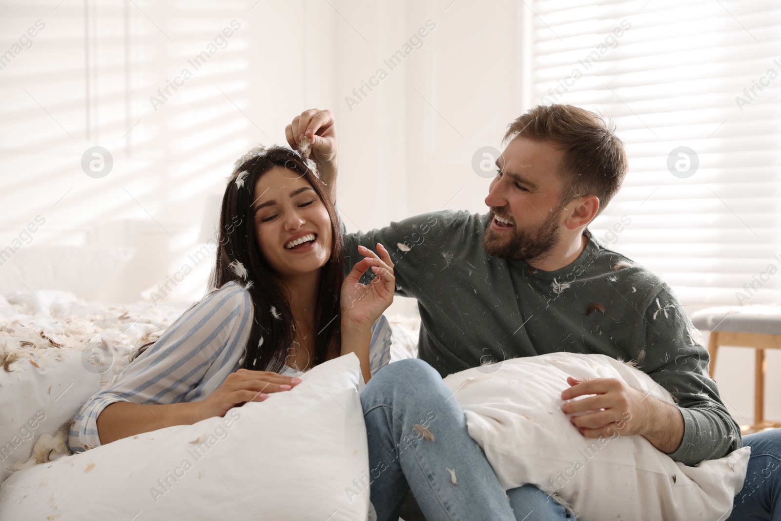 Photo of Happy young couple resting after fun pillow fight in bedroom