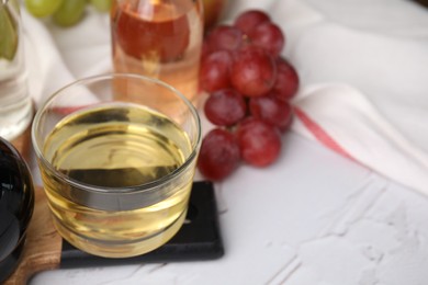 Different types of vinegar and grapes on white table, space for text