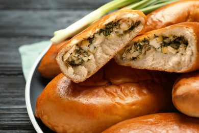 Many delicious baked patties with eggs and herbs on wooden table, closeup