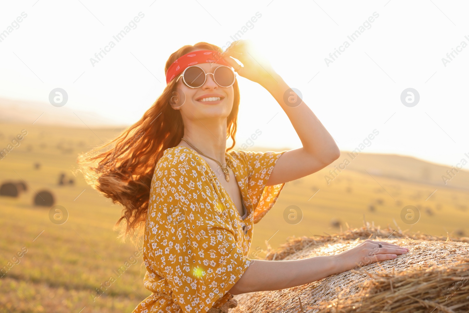 Photo of Happy hippie woman near hay bale in field