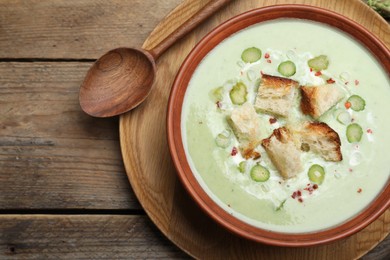 Photo of Delicious asparagus soup with croutons served on wooden table, top view
