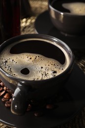 Cup of coffee and beans on serving tray, closeup