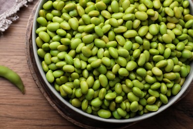 Bowl of delicious edamame beans on wooden table, top view