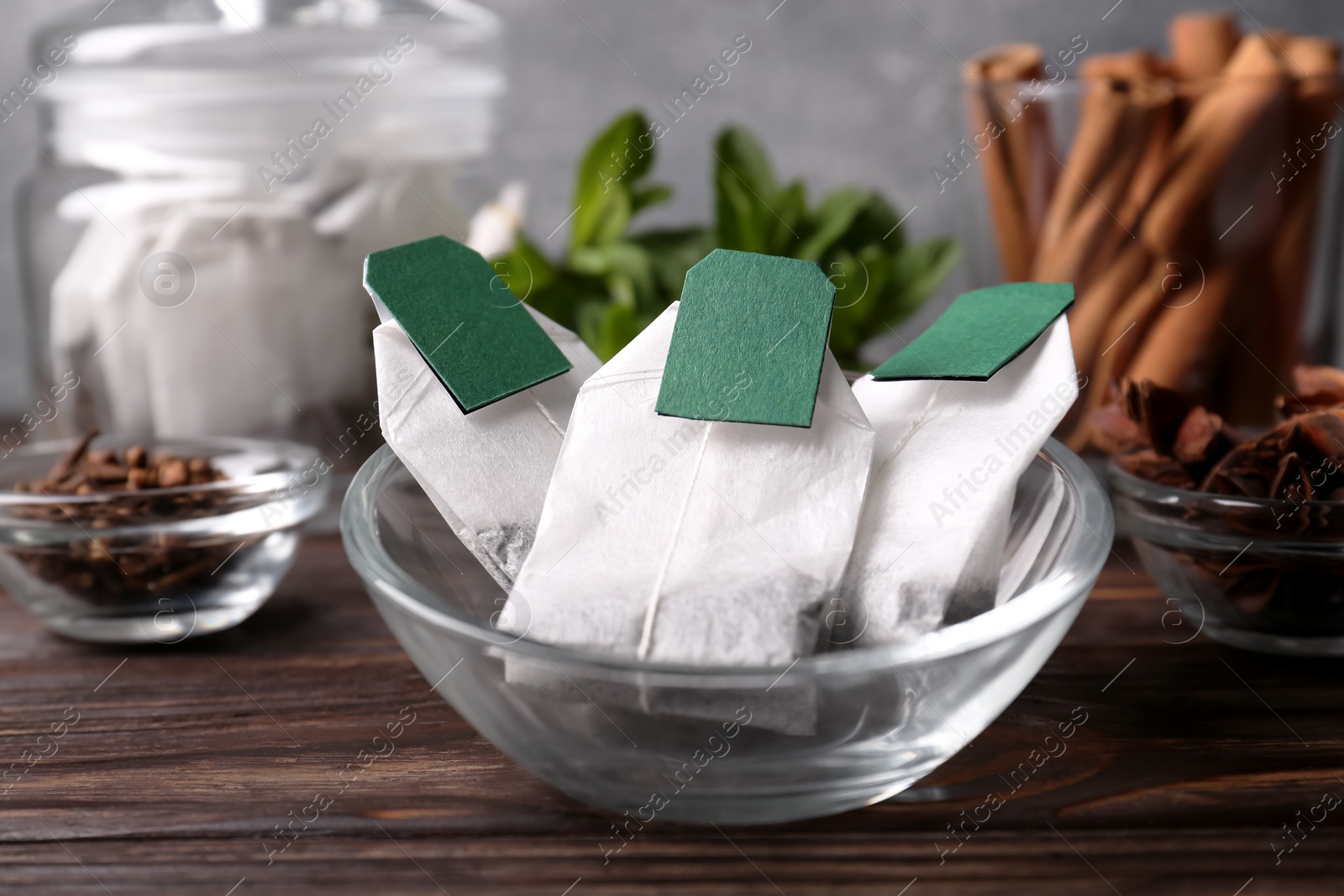 Photo of Tea bags and ingredients on wooden table, closeup
