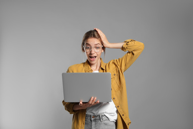 Photo of Portrait of emotional woman with modern laptop on grey background