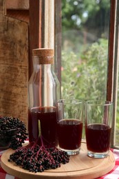 Photo of Elderberry drink and Sambucus berries on table near window