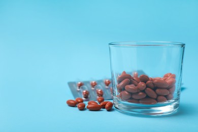 Photo of Glass with pills on turquoise background, space for text. Anemia treatment