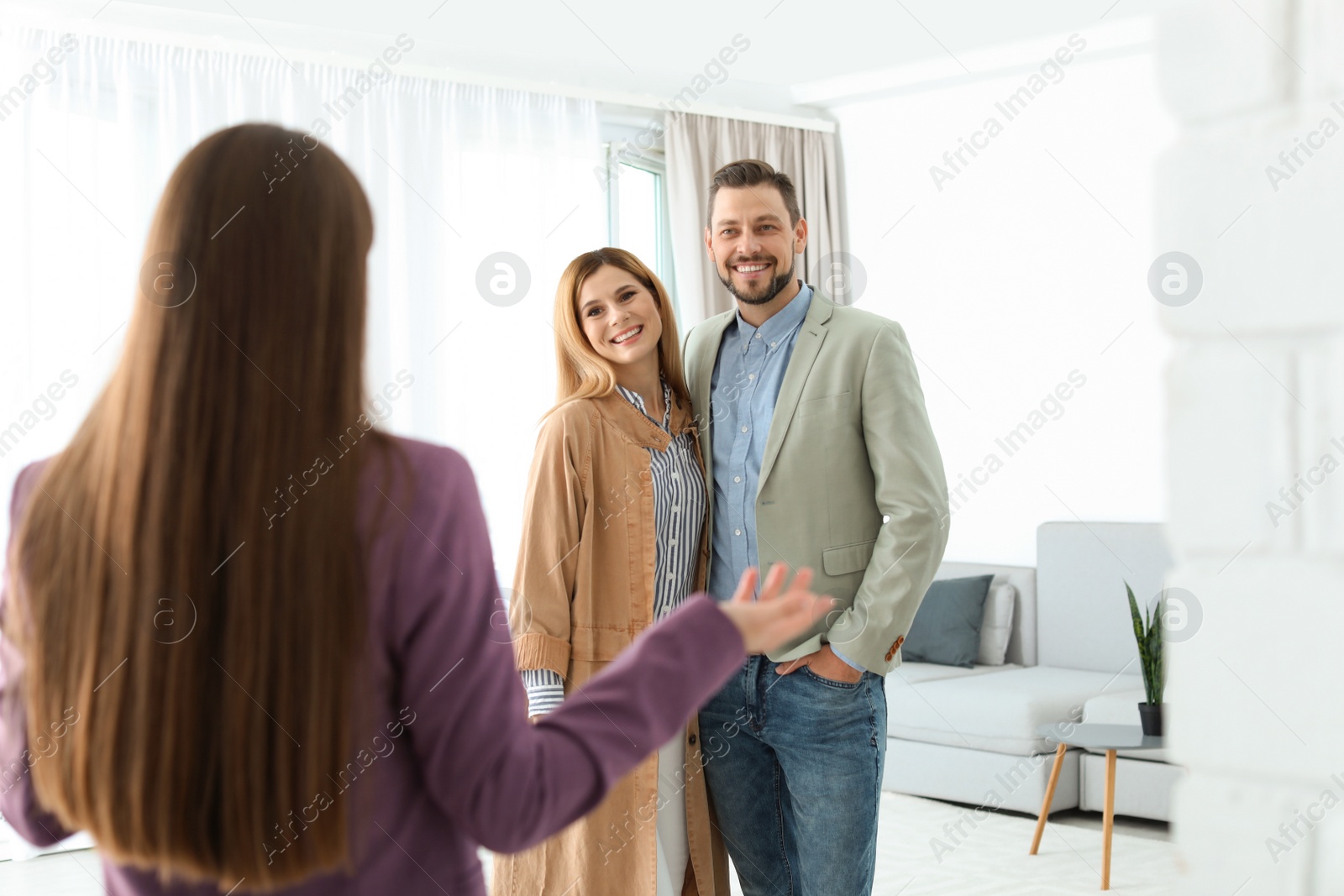 Photo of Female real estate agent showing new house to couple, indoors