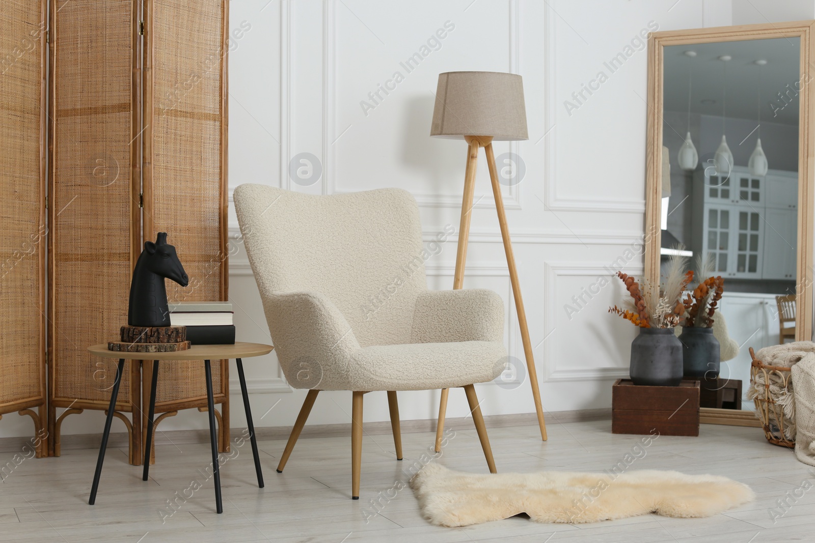 Photo of Stylish beige armchair, small coffee table and mirror in living room. Interior design