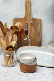 Different kitchenware and dishware on white wooden table against textured wall