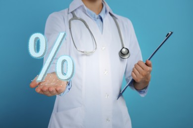 Image of Discount offer. Doctor with stethoscope and clipboard holding percent sign on light blue background, closeup