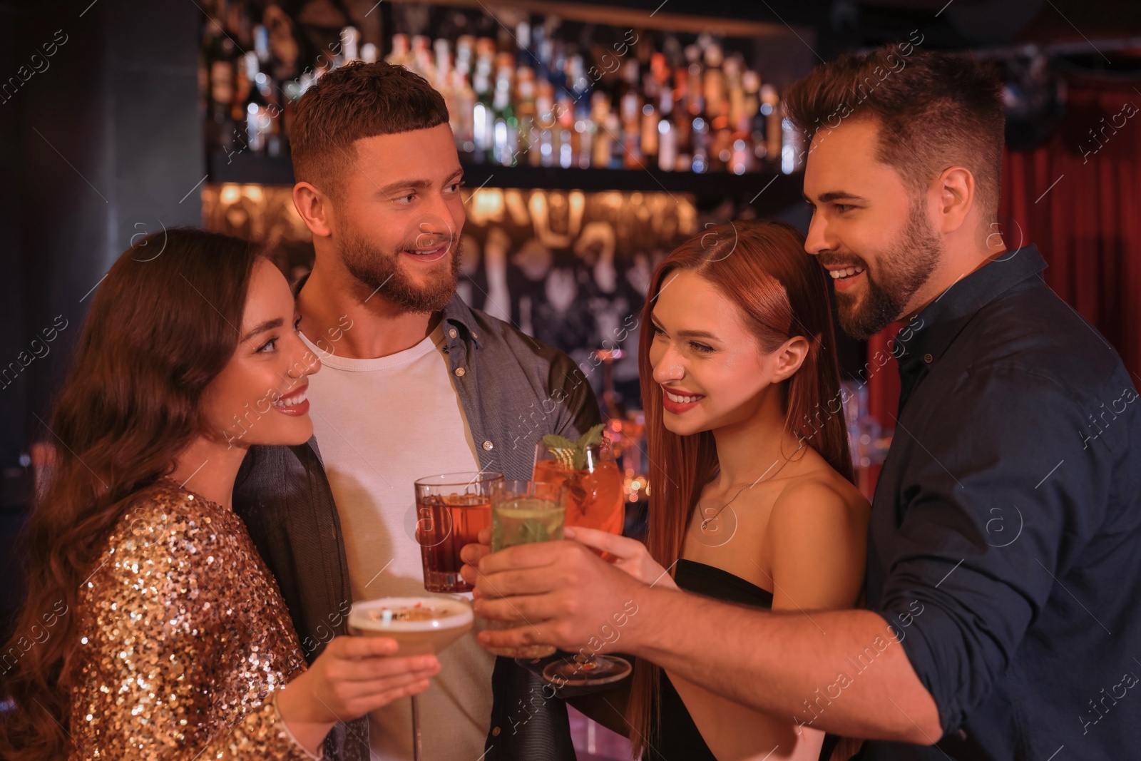 Photo of Happy friends clinking glasses with fresh cocktails in bar