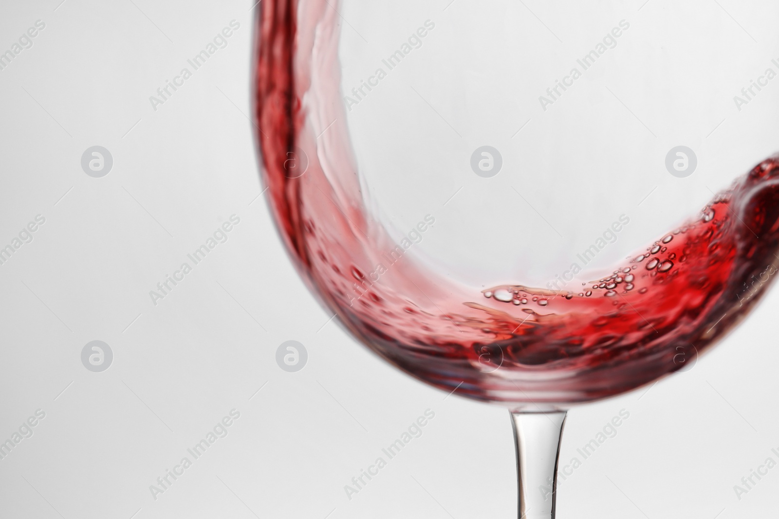 Photo of Pouring red wine into glass on light background, closeup