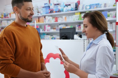Photo of Professional pharmacist working with customer in drugstore