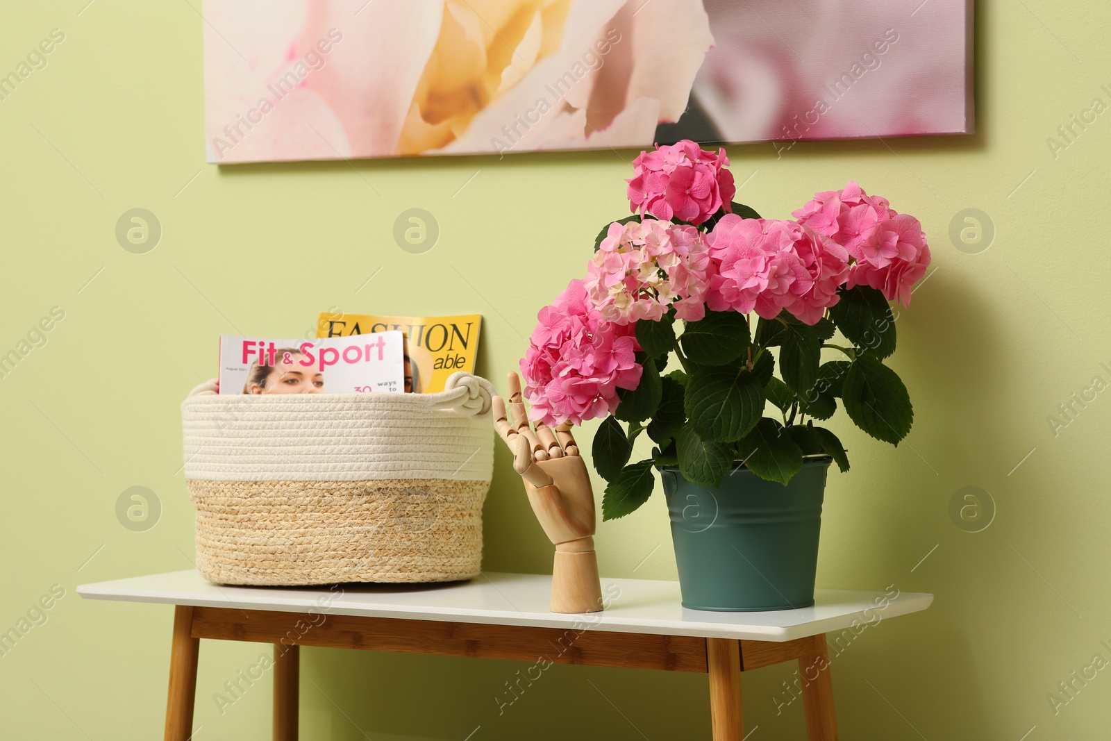 Photo of Console table with beautiful hortensia flower near light green wall in hallway. Interior design