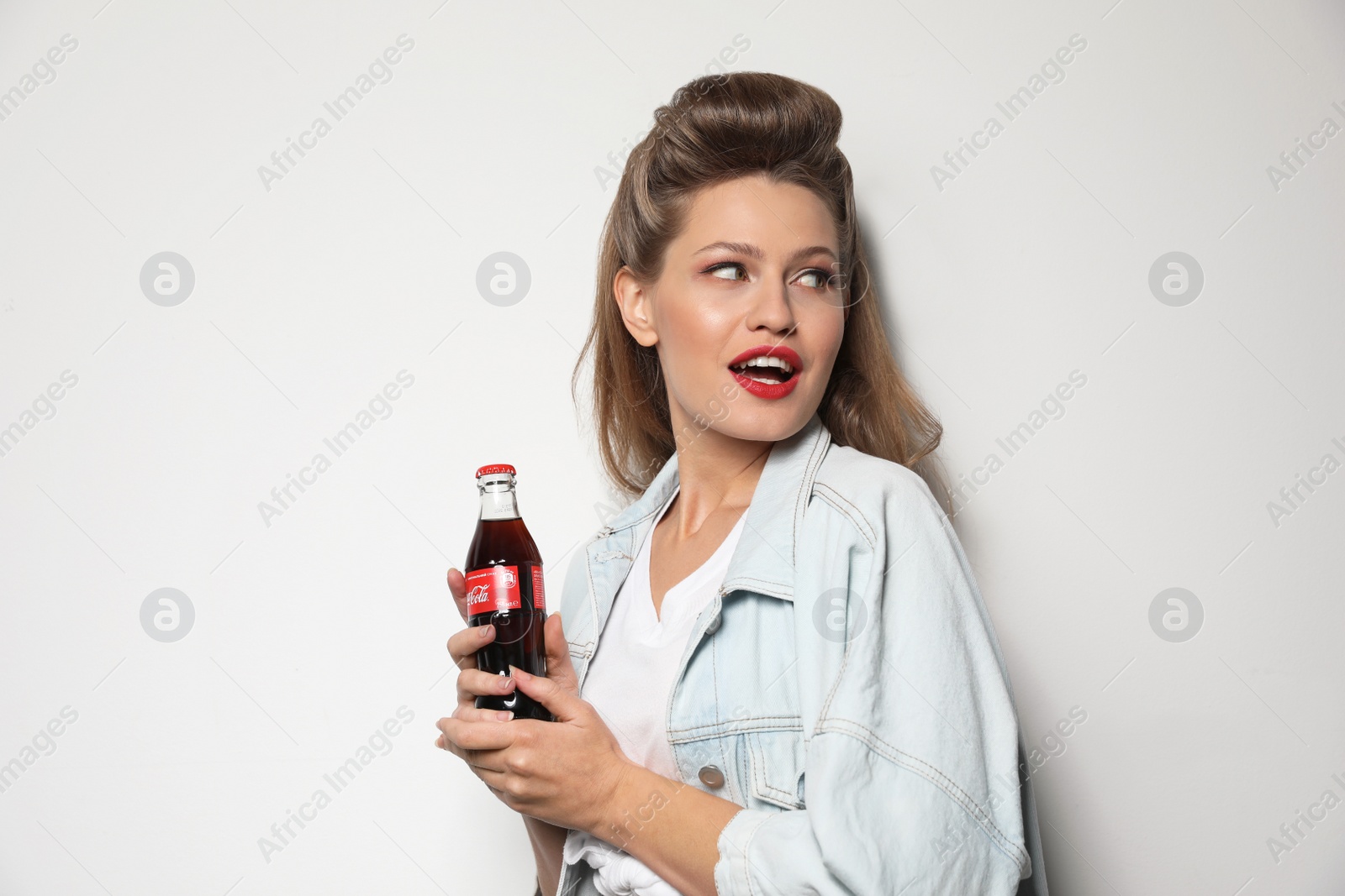 Photo of MYKOLAIV, UKRAINE - NOVEMBER 28, 2018: Young woman with bottle of Coca-Cola on white background