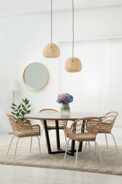 Table, chairs and vase of hydrangea flowers in dining room. Stylish interior