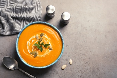 Photo of Flat lay composition with bowl of pumpkin soup and space for text on gray background