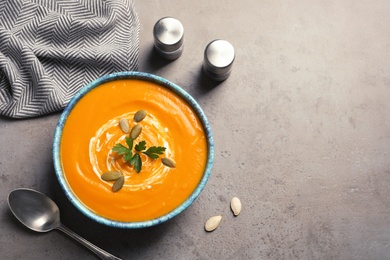 Flat lay composition with bowl of pumpkin soup and space for text on gray background