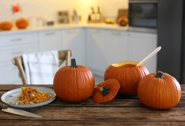 Photo of Fresh ripe pumpkins on wooden table in kitchen, space for text. Halloween celebration