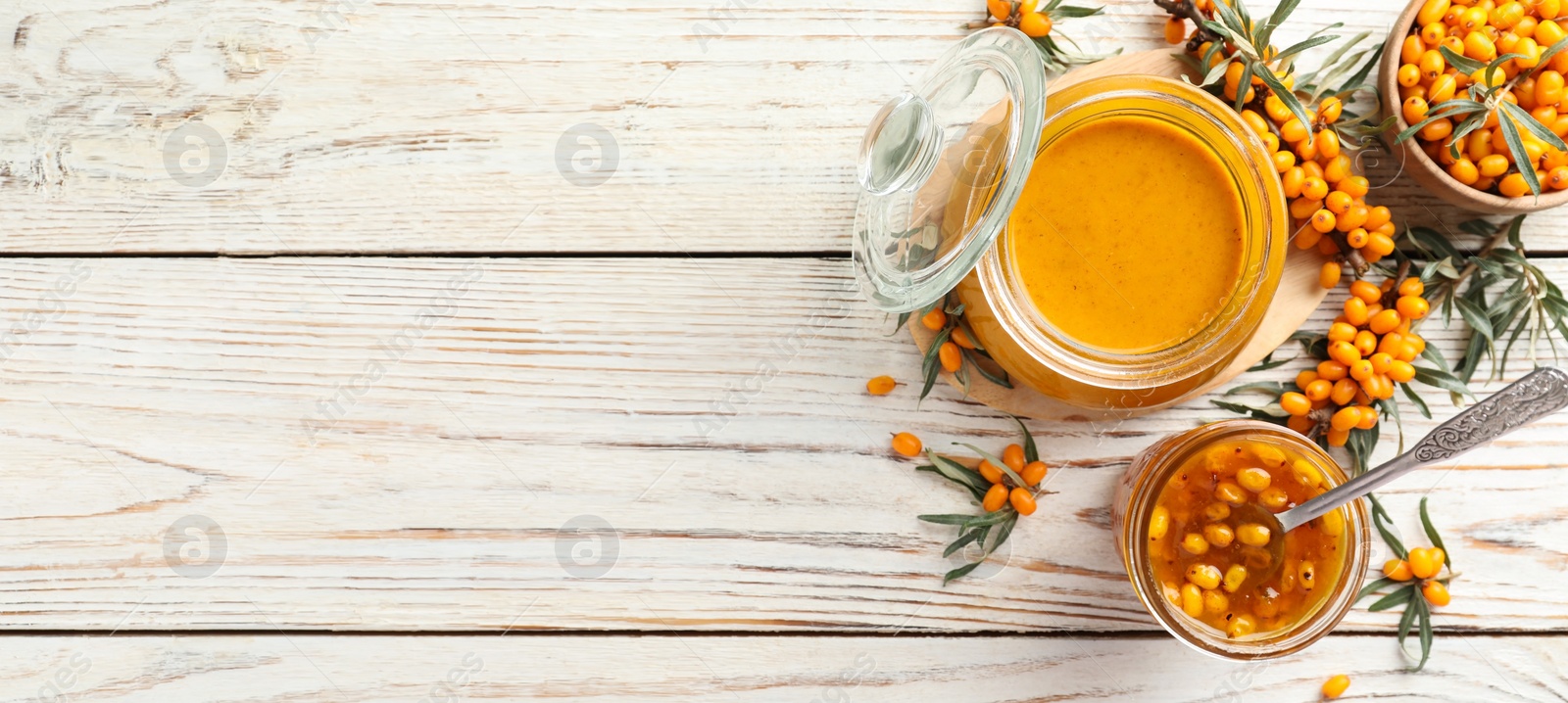 Image of Delicious sea buckthorn jam and fresh berries on white wooden table, flat lay. Banner design with space for text