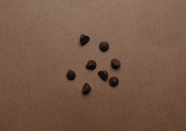 Photo of Delicious chocolate chips on brown background, top view