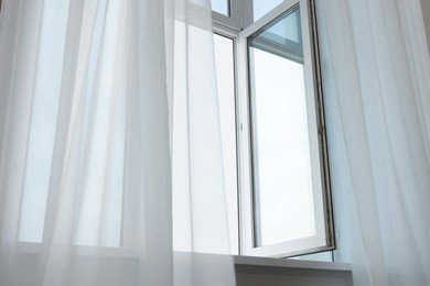Photo of Open window and elegant white curtains indoors. Interior design