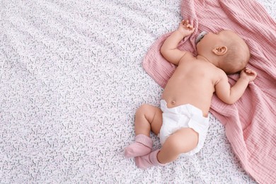 Photo of Little baby in diaper on bed, top view. Space for text