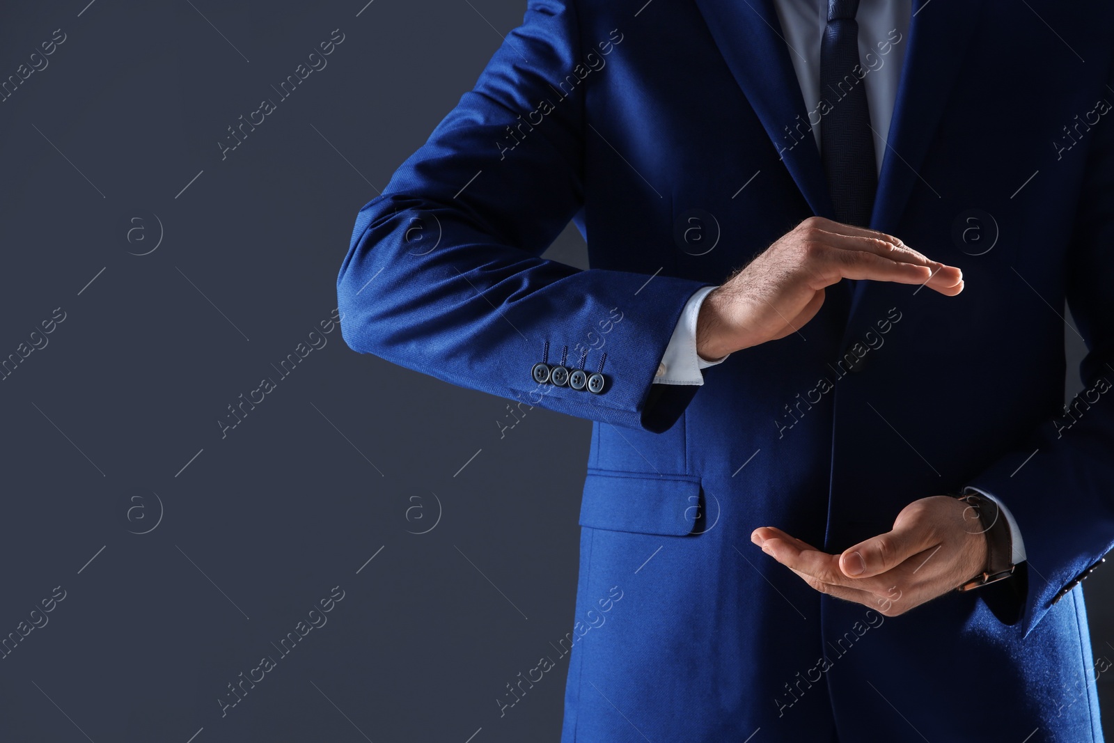 Photo of Businessman holding something in hands on dark background