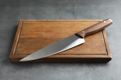 Photo of Knife and wooden board on grey textured table