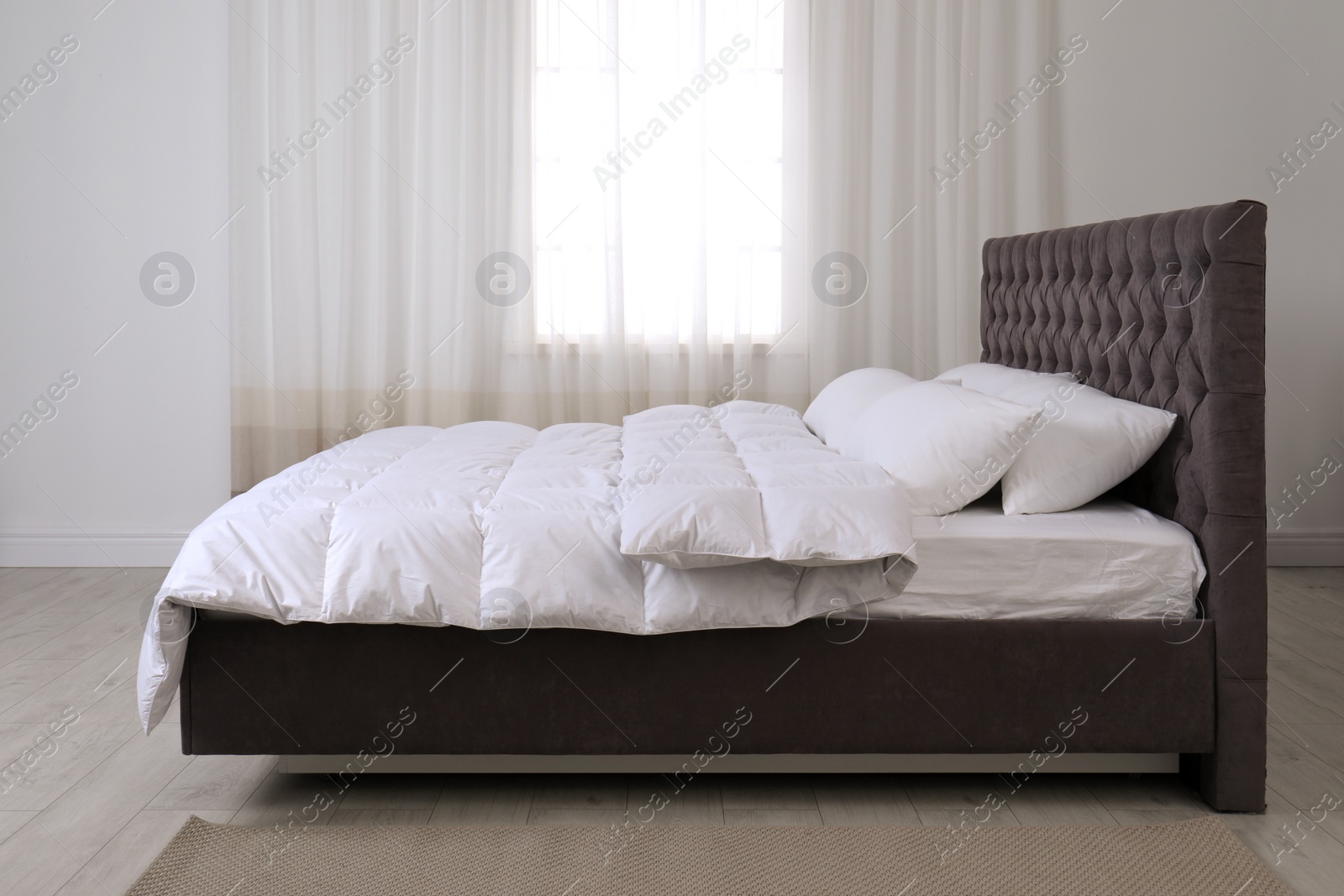 Photo of Large comfortable bed in light room. Stylish interior