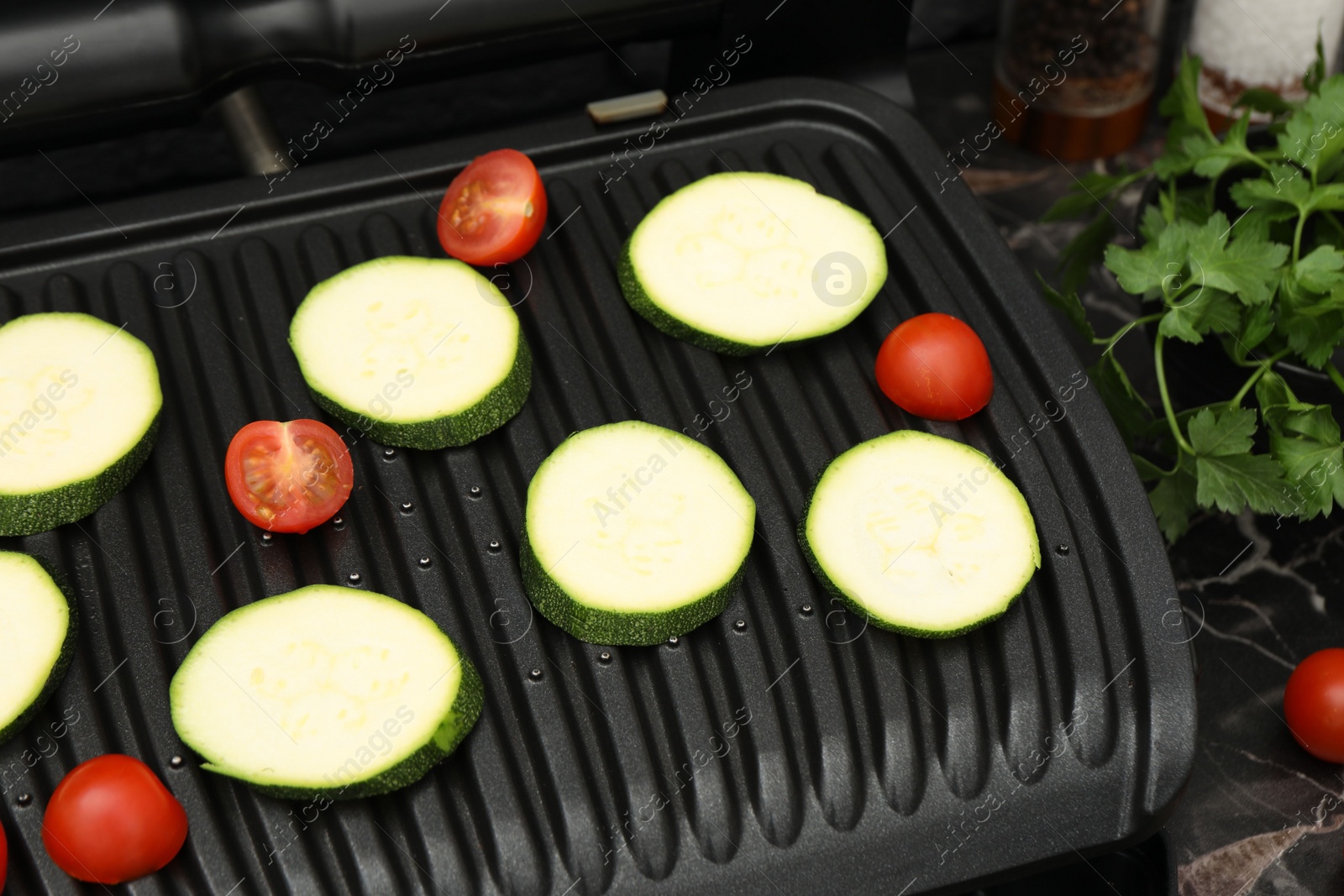 Photo of Electric grill with vegetables on black table, closeup