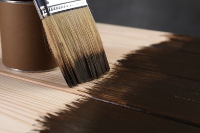 Photo of Applying wood stain with brush onto wooden surface, closeup. Space for text
