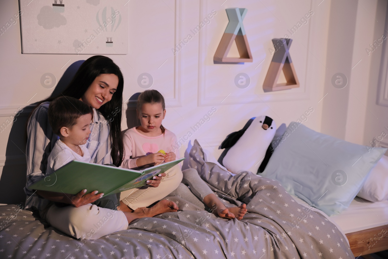 Photo of Mother reading bedtime story to her children at home