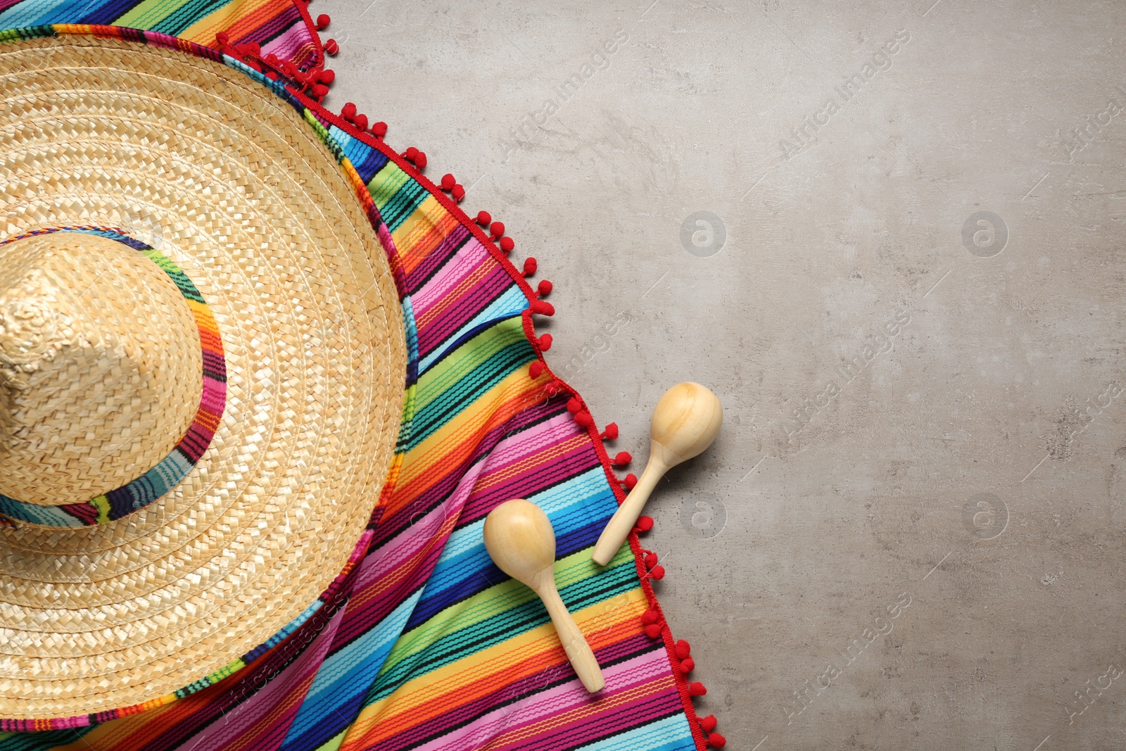 Photo of Mexican sombrero hat, maracas and colorful poncho on grey textured background, flat lay. Space for text