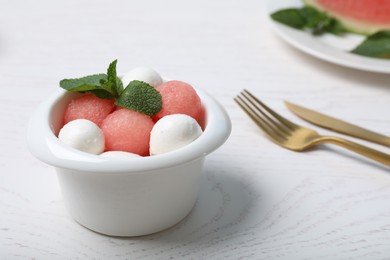 Photo of Delicious salad with watermelon balls, mint and mozzarella served on white wooden table, closeup