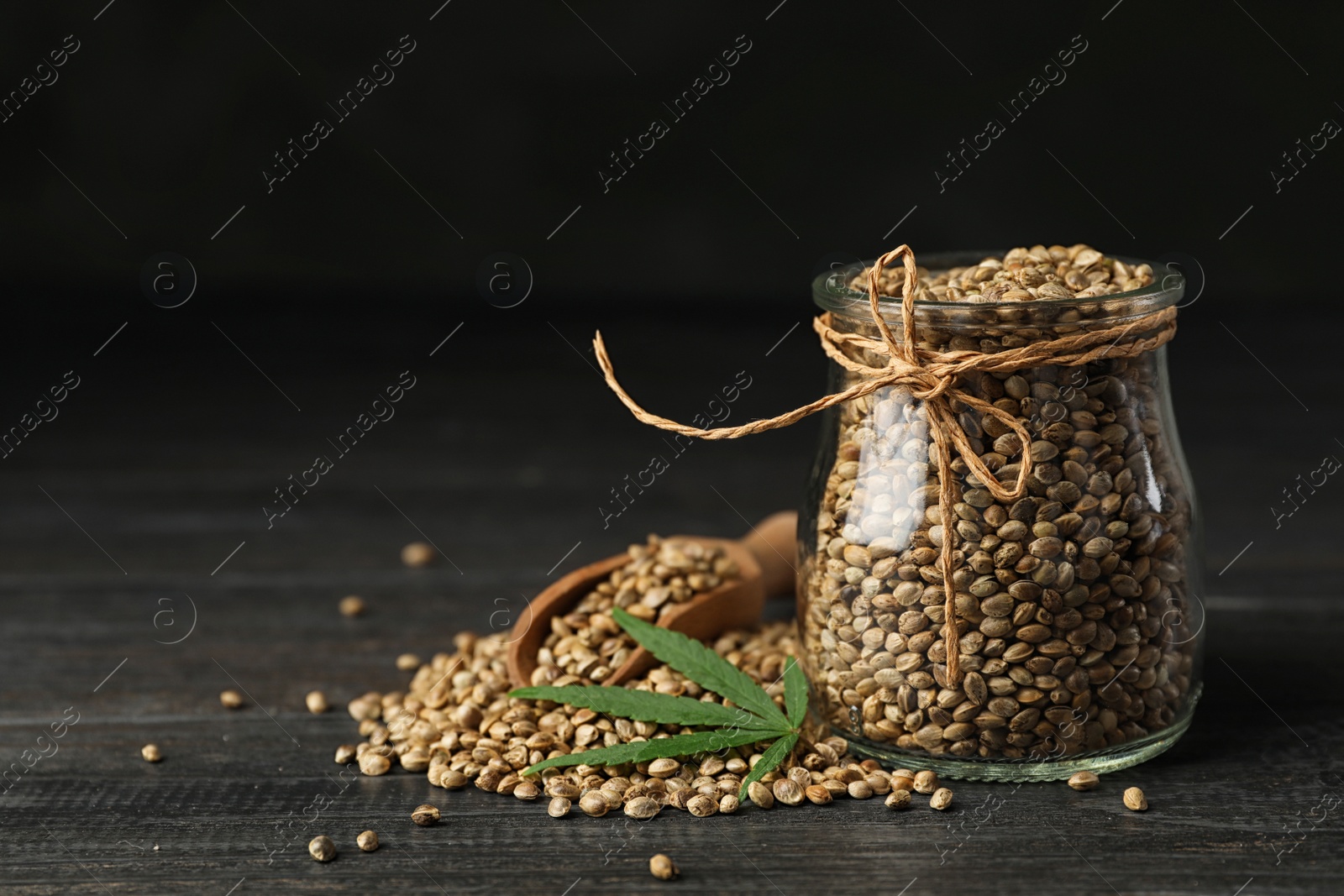 Photo of Organic hemp seeds and leaf on black wooden table