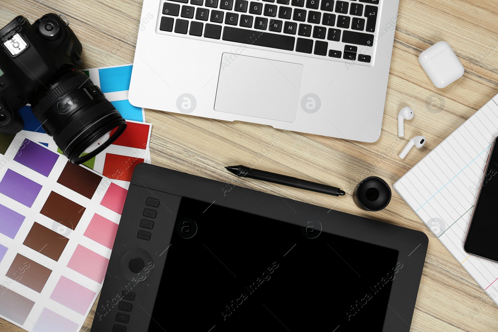 Photo of Flat lay composition with graphic tablet, camera and color palettes on wooden table, space for text. Designer's workplace