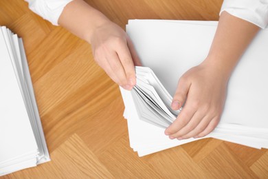 Man stacking documents at wooden table, top view