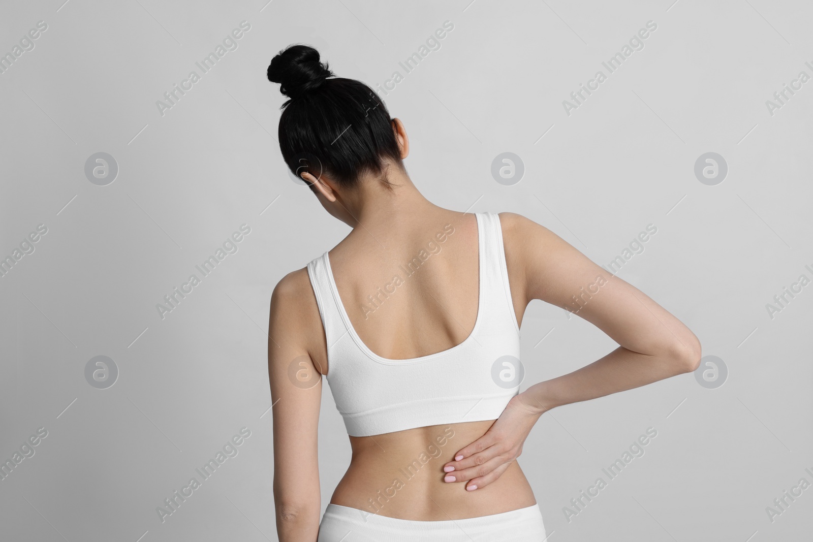 Photo of Woman suffering from pain in back on light background