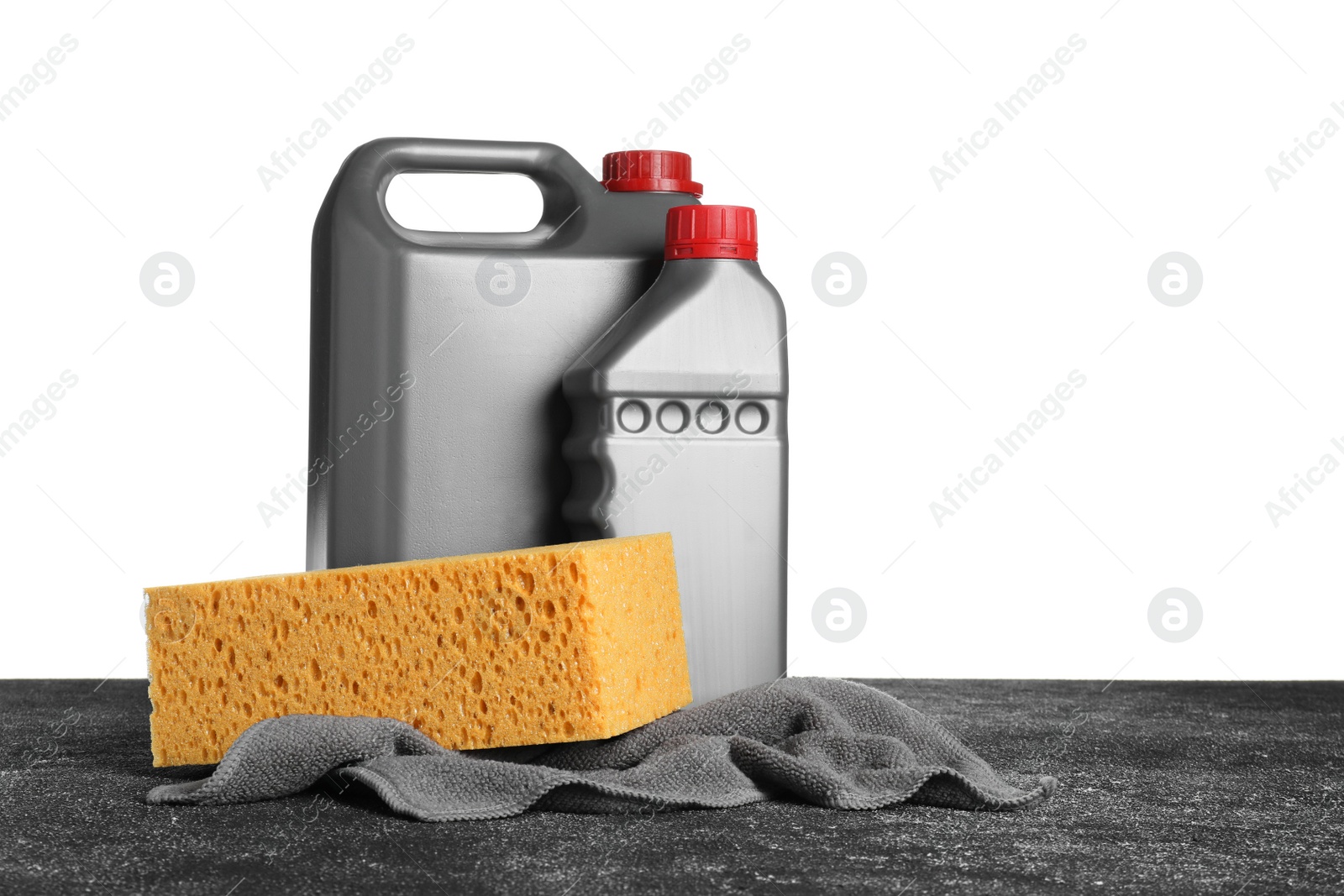 Photo of Bottles, cloth and car wash sponge on black table against white background