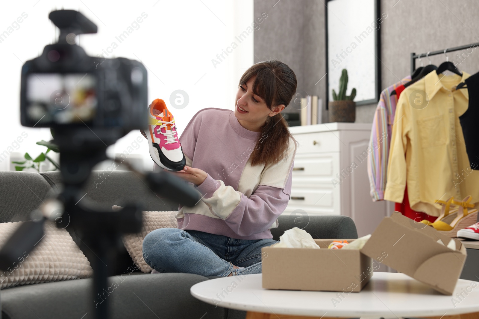 Photo of Smiling fashion blogger showing her shoes while recording video at home