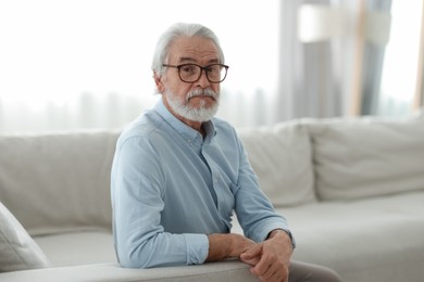 Portrait of grandpa with stylish glasses on sofa indoors