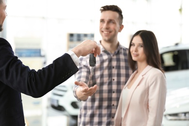 Young couple buying new car in salon