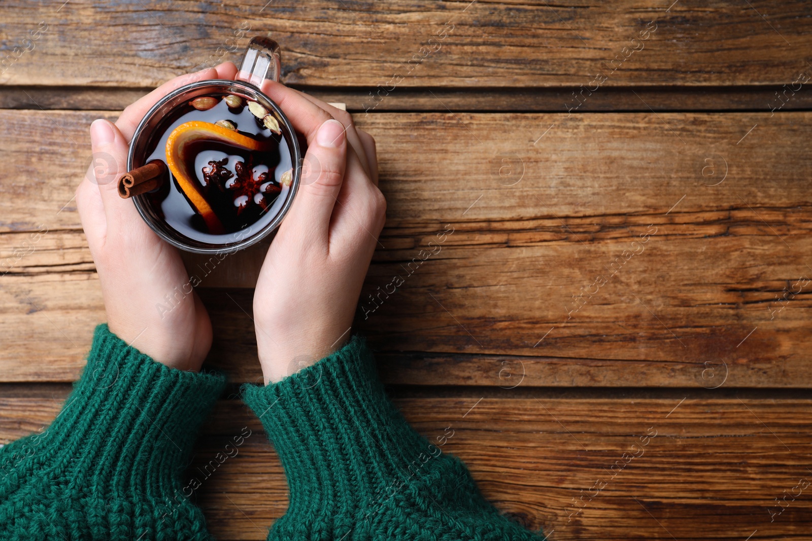 Photo of Woman with cup of mulled wine at wooden table, top view. Space for text