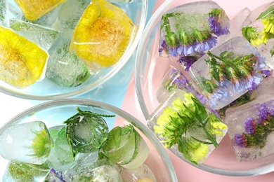 Photo of Bowls of ice cubes with flowers on color background, flat lay